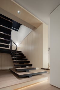 A modern staircase featuring black wood steps and a black metal railing, set within a contemporary interior design environmen