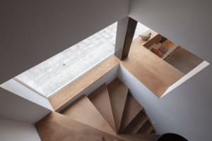 Minimalist interior design featuring a wooden staircase with a skylight and kitchen area.