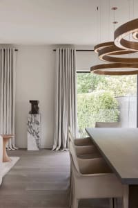 Modern, minimalist residential interior featuring clean lines, neutral tones, and a large window.