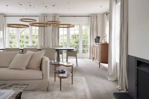 Modern living room with neutral tones, featuring a comfortable sofa, a sleek coffee table, and a dining table with chairs.