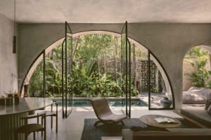 Modern residential interior featuring concrete walls and glass doors with a view of a pool and garden.