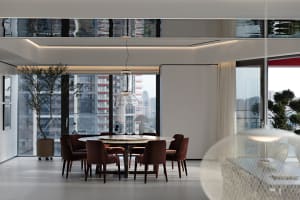 A modern dining room featuring a round table and chairs surrounded by a glass window.