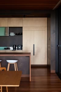 Modern minimalist kitchen featuring wood cabinets and flooring.