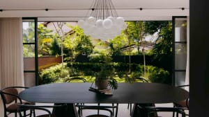 Modern residential dining room featuring a black oval table with chairs, a white balloon cloud chandelier, and a green outdoo