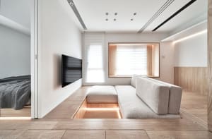 Modern living room interior with a built-in platform, wooden floor, and furniture.
