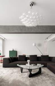 Modern living room with a concrete ceiling beam, a black sectional sofa, and a glass coffee table.