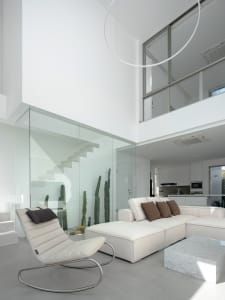 A modern living room featuring glass walls, concrete flooring, and minimalist furniture.