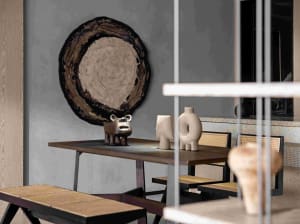 Modern dining room featuring a wooden table and chairs, with decorative items on the table and a large, circular wood slice w