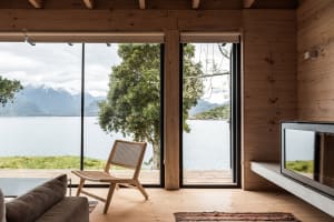 A modern wooden living room with a view of the lake and mountains.