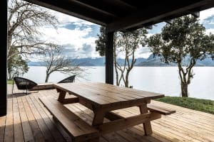 Wooden picnic table on a deck overlooking a lake