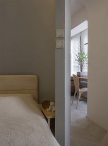 A minimalist bedroom featuring a wooden nightstand with a clock and a stuffed animal.