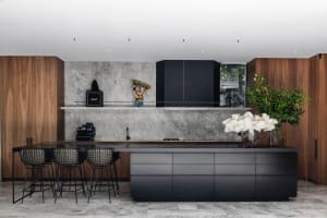 Contemporary kitchen with concrete countertops, black cabinetry, and a black countertop.