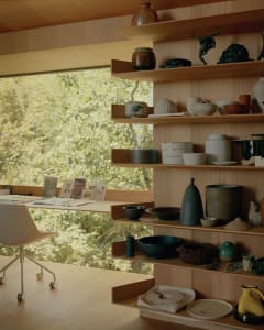 A well-organized craft shop displaying various ceramic pottery and sculptures on wooden shelves.