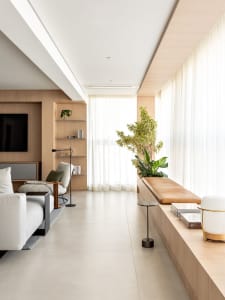 A modern living room with light wood laminate flooring, white walls, and a minimalist design.