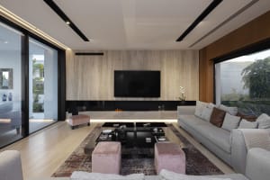 Modern minimalist living room with sleek furniture, wooden walls, and glass windows.