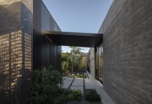 Modern entranceway with concrete walls and a metal walkway.
