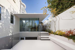 Modern, minimalist glass extension with white walls and outdoor space.