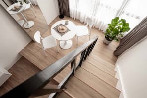 A minimalist dining area with white furniture, light wood flooring, and green plants.