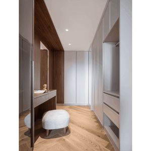 A modern closet featuring wood cabinets and glass doors.