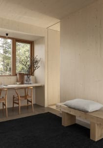 Minimalist bedroom with wooden walls, a wooden bench, and a black rug.