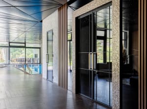 Modern indoor swimming pool entry featuring glass doors and sleek design.