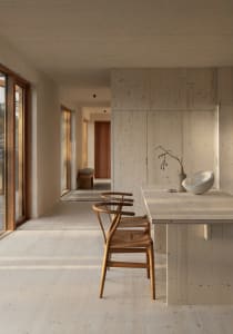 A modern minimalist kitchen featuring wooden finishes and a central island with a white bowl and vase.