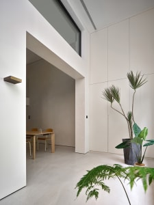 Modern minimalist living room with concrete walls, wood furniture, and large windows.