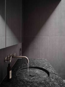 Black granite countertop with a contemporary faucet in a minimalist bathroom