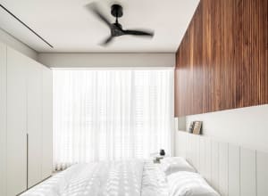 A modern bedroom featuring white bedding on a wood headboard, with a large window covered by sheer curtains.