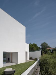 A minimalist, modern house with white stucco exterior walls and a bright blue sky.