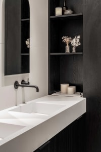 Modern bathroom with a sleek, minimalist design featuring a concrete counter and black shelving.
