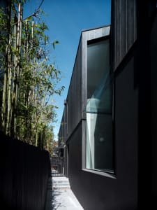 Modern house with dark concrete exterior and large glass window.