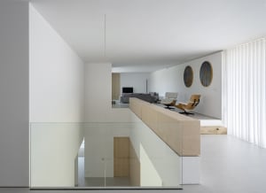 Modern living room with concrete floor, glass walls, and wooden furniture.