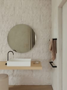 Modern minimalist bathroom with stone walls, a round mirror, a rectangular sink, and a towel bar.