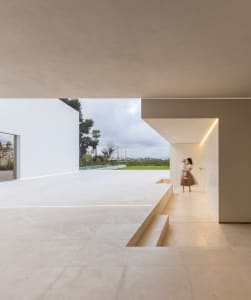 Modern minimalist residential interior with concrete floor and walls and glass walls and doors.
