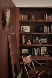 A minimalist library with wooden shelves, books, and sculptures