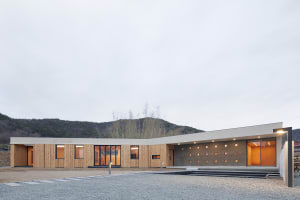 Modern house with wooden and concrete exterior and large glass windows.