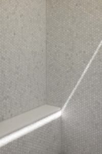 A modern bathroom with hexagonal tile walls and a built-in bench.