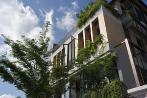 A modern building with a concrete exterior and lush greenery.