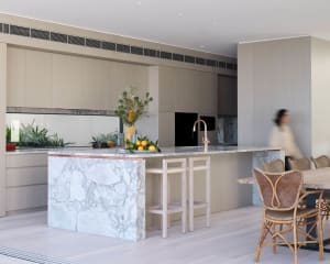 Modern minimalist kitchen featuring a marble island, wood cabinets, and copper accents.