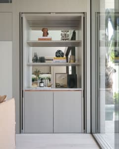 A modern bar with built-in shelves and a marble countertop, featuring various decorative and functional items.