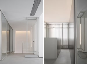 Modern office space featuring glass walls, minimalist design, and white interior.