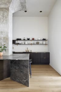 Modern kitchen with marble countertops and black cabinets.
