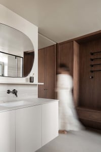 A modern minimalist bathroom with a wooden vanity and porcelain sink, featuring clean lines and a round mirror.
