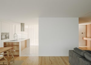 A minimalist living room featuring white walls, wooden furniture, marble flooring, and metallic accents.