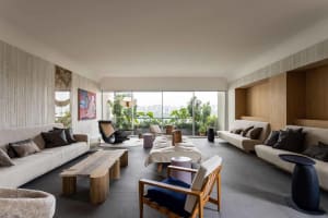 A modern living room featuring white sofas, wooden furniture, and a mix of materials.