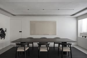 Modern dining room featuring wooden table and black chairs with leather cushions.