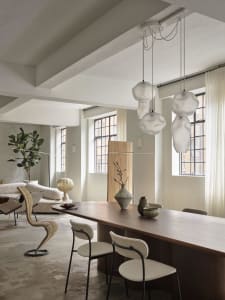 Modern living and dining room featuring wood furniture, glass pendant lights, and concrete flooring.