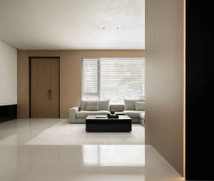 Modern minimalist living room with light wooden walls, white sofa, and black coffee table with a book and remote.
