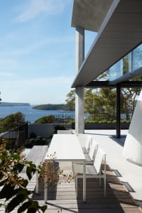 Modern patio featuring a wooden deck and metal frame furniture overlooking a scenic waterfront view.